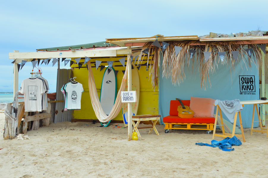 SWAKiKO surf shop op Sorobon, Bonaire – ingericht met shirts, boards, een bankje, gitaar en slingers